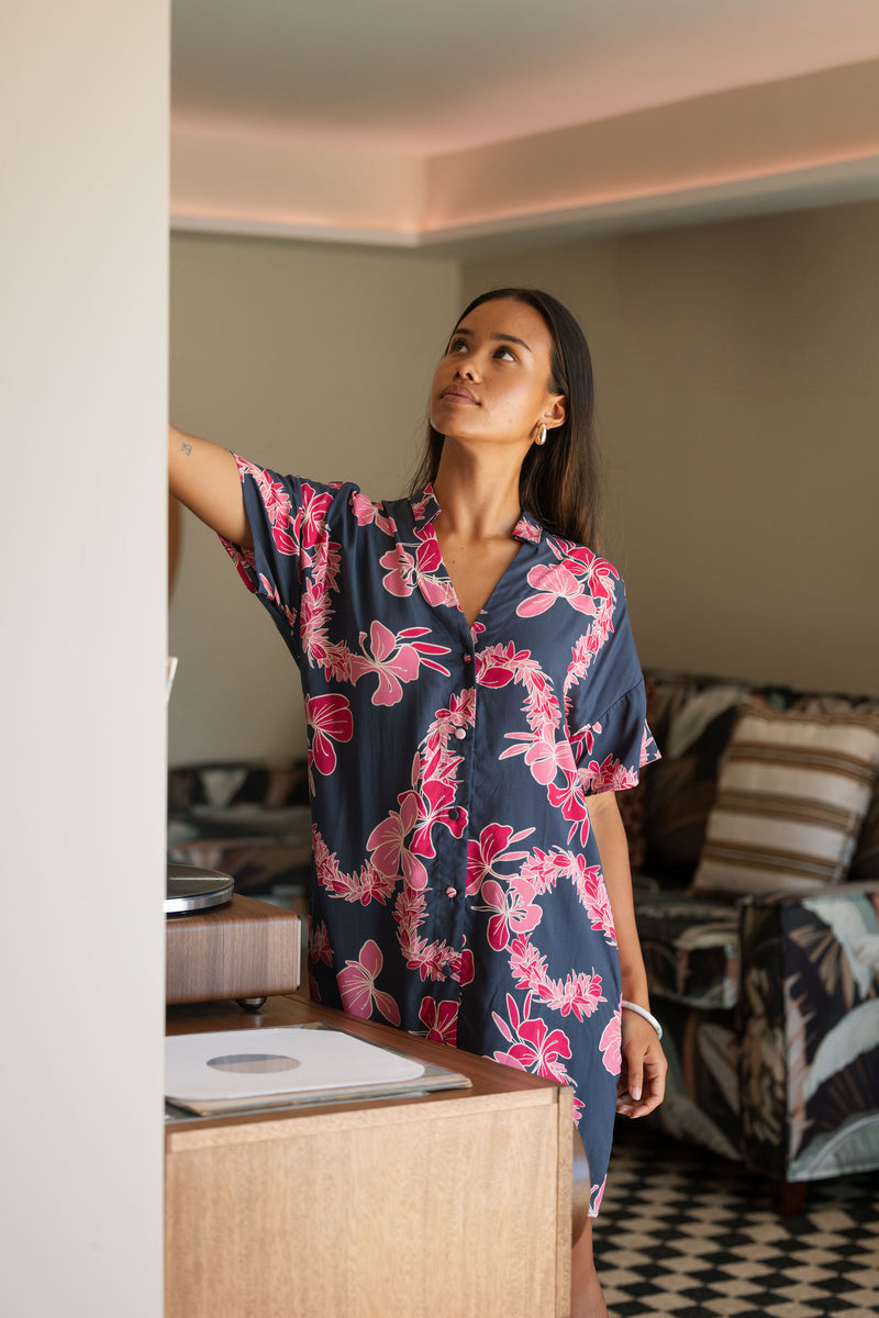 Woman in an above the knee shirt dress with dark navy ground and pink ginger and lei print.