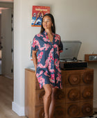 Woman in an above the knee shirt dress with dark navy ground and pink ginger and lei print.