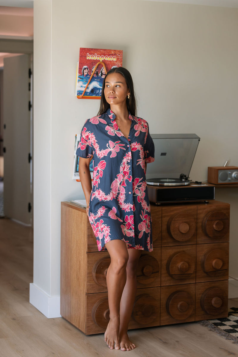 Woman in an above the knee shirt dress with dark navy ground and pink ginger and lei print.