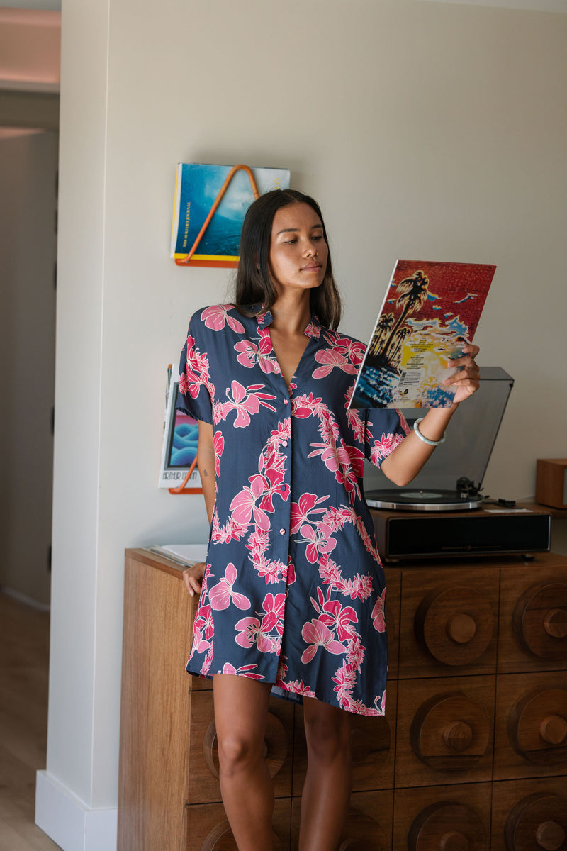 Woman in an above the knee shirt dress with dark navy ground and pink ginger and lei print.