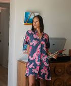 Woman in an above the knee shirt dress with dark navy ground and pink ginger and lei print.