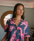 Woman in an above the knee shirt dress with dark navy ground and pink ginger and lei print.