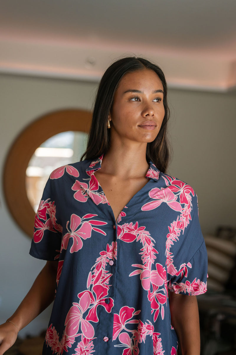 Woman in an above the knee shirt dress with dark navy ground and pink ginger and lei print.