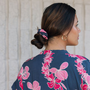 Woman with scrunchie in hair in navy with pink ginger and lei print.