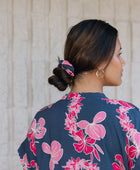 Woman with scrunchie in hair in navy with pink ginger and lei print.