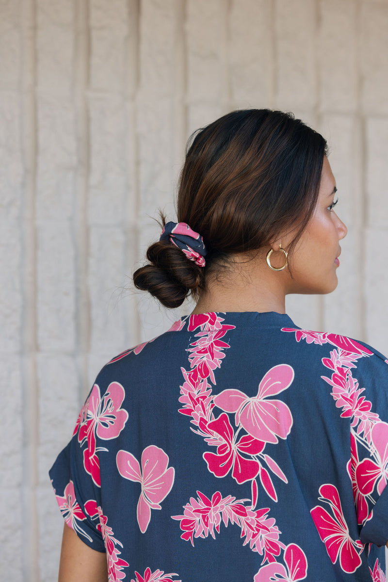 Woman with scrunchie in hair in navy with pink ginger and lei print.