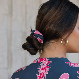 Woman with scrunchie in hair in navy with pink ginger and lei print.