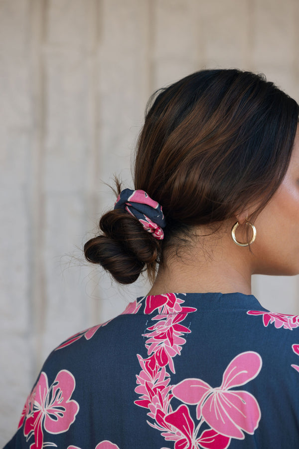 Woman with scrunchie in hair in navy with pink ginger and lei print.