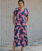 Woman in a long shirt dress with dark navy ground and pink ginger and lei print.