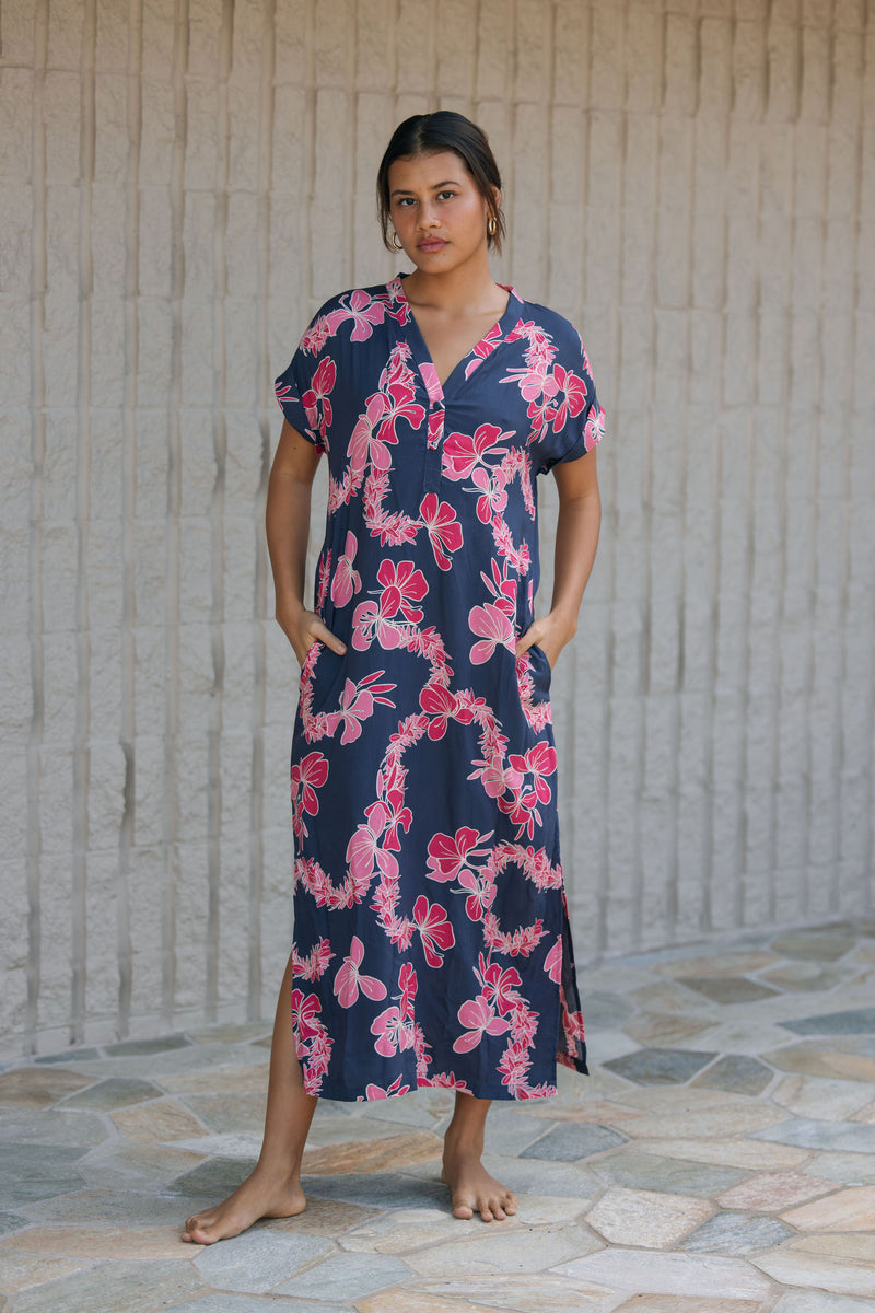 Woman in a long shirt dress with dark navy ground and pink ginger and lei print.