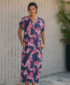 Woman in a long shirt dress with dark navy ground and pink ginger and lei print.