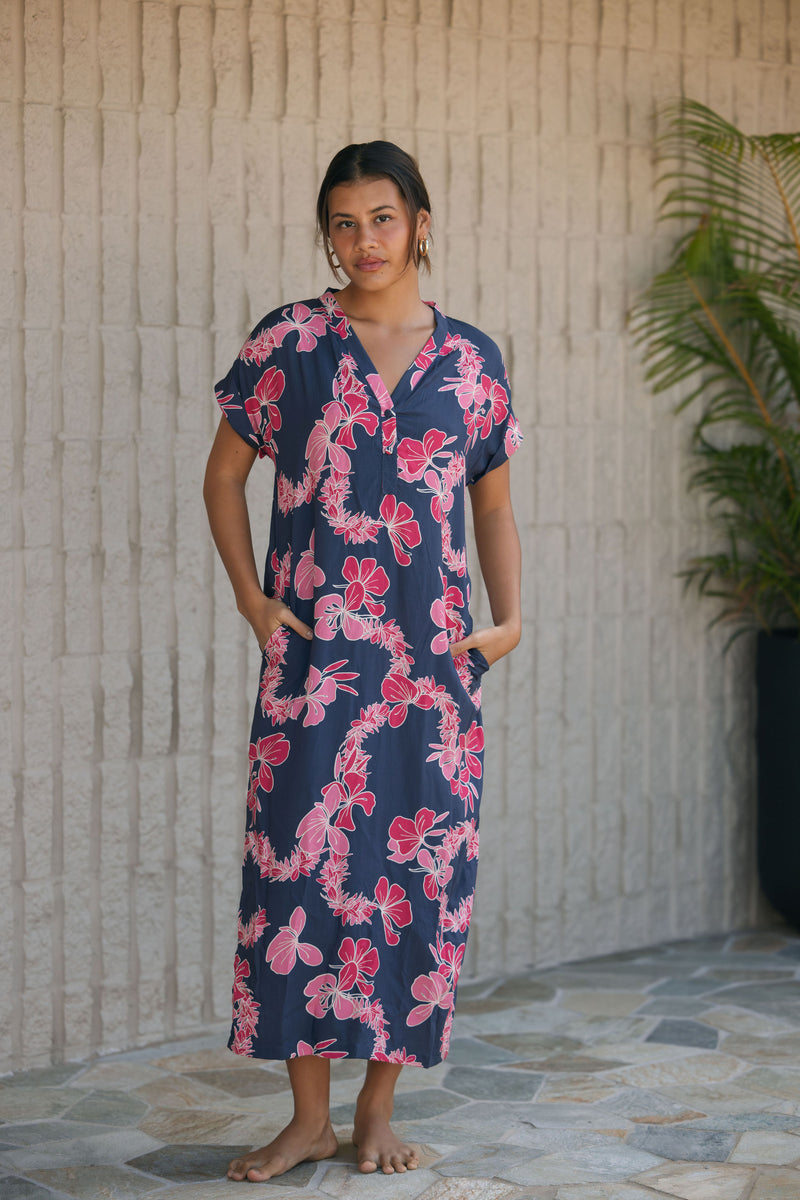 Woman in a long shirt dress with dark navy ground and pink ginger and lei print.