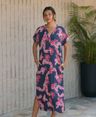 Woman in a long shirt dress with dark navy ground and pink ginger and lei print.