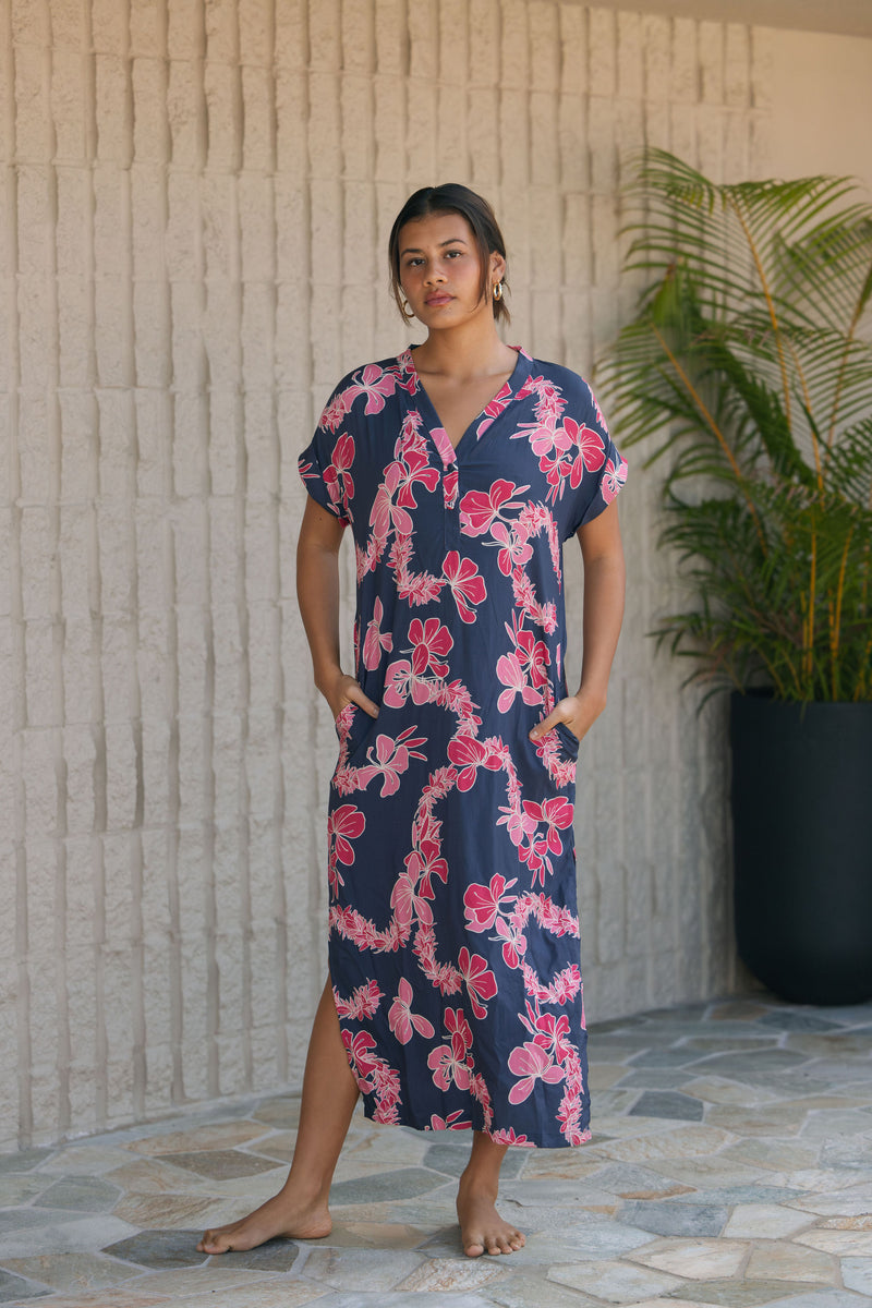 Woman in a long shirt dress with dark navy ground and pink ginger and lei print.