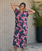 Woman in a long shirt dress with dark navy ground and pink ginger and lei print.