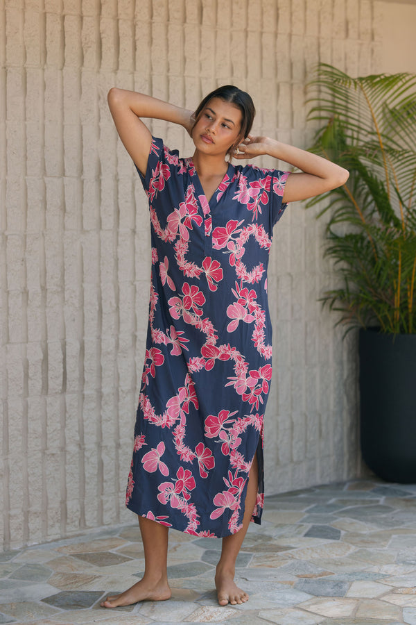 Woman in a long shirt dress with dark navy ground and pink ginger and lei print.