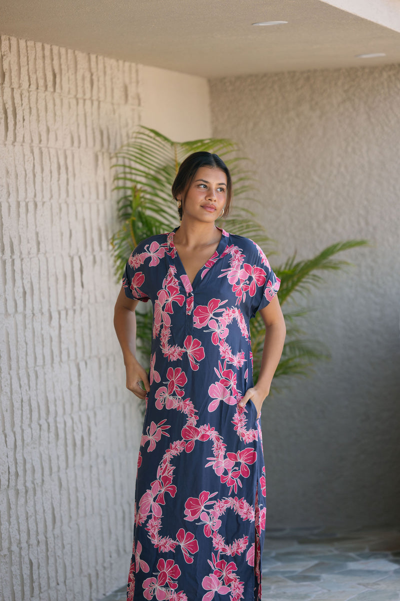 Woman in a long shirt dress with dark navy ground and pink ginger and lei print.