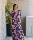 Woman in a long shirt dress with dark navy ground and pink ginger and lei print.