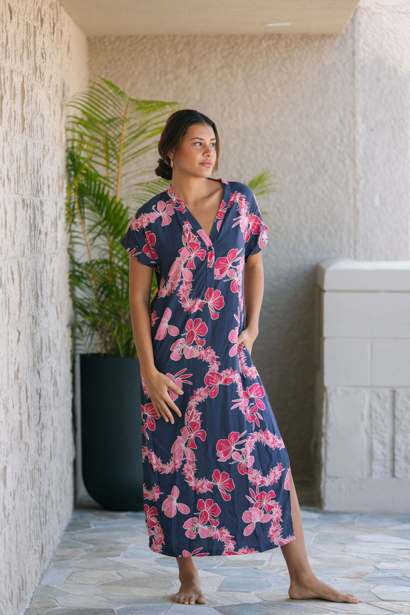 Woman in a long shirt dress with dark navy ground and pink ginger and lei print.