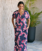 Woman in a long shirt dress with dark navy ground and pink ginger and lei print.