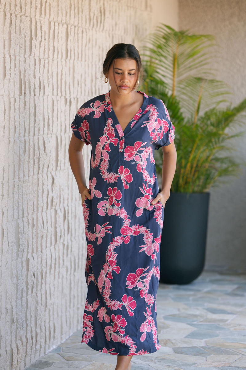 Woman in a long shirt dress with dark navy ground and pink ginger and lei print.