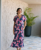 Woman in a long shirt dress with dark navy ground and pink ginger and lei print.