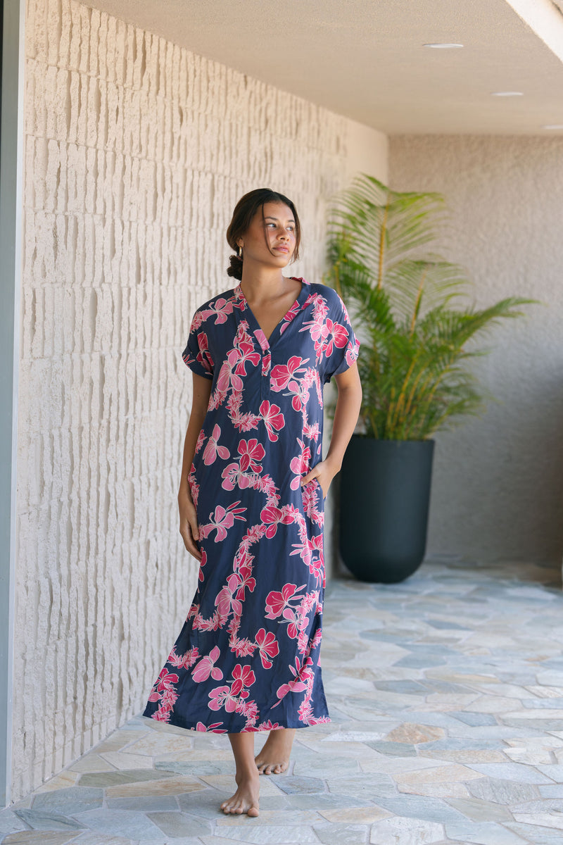 Woman in a long shirt dress with dark navy ground and pink ginger and lei print.