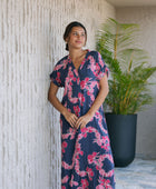 Woman in a long shirt dress with dark navy ground and pink ginger and lei print.