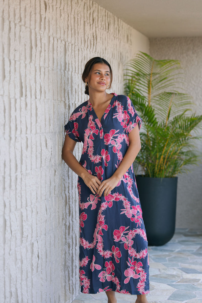 Woman in a long shirt dress with dark navy ground and pink ginger and lei print.