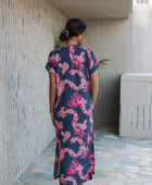 Woman in a long shirt dress with dark navy ground and pink ginger and lei print.