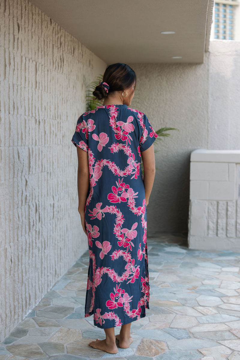 Woman in a long shirt dress with dark navy ground and pink ginger and lei print.