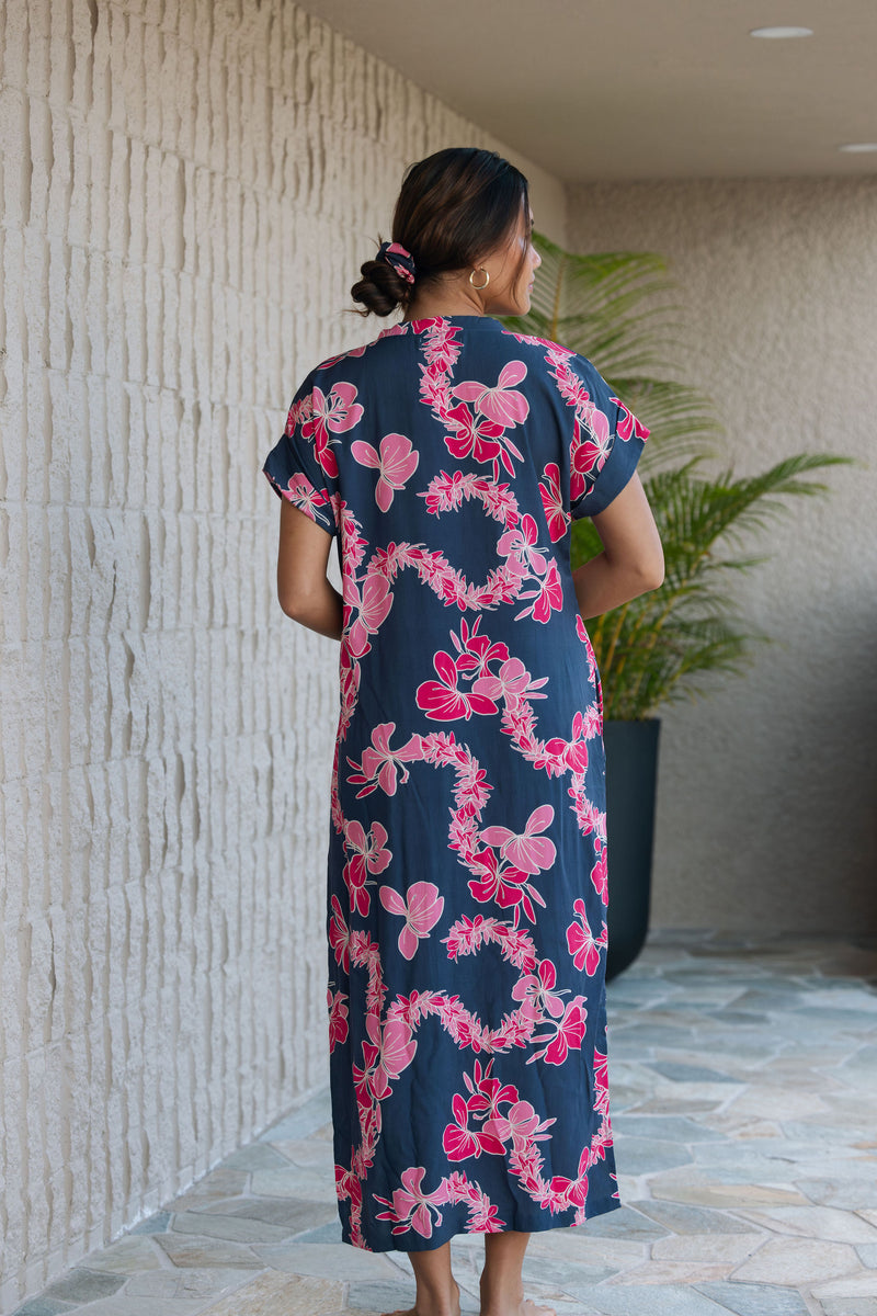 Woman in a long shirt dress with dark navy ground and pink ginger and lei print.