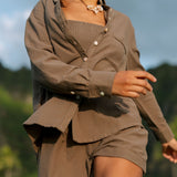 Woman wearing loose button up, smocked tube top and short in medium brown linen.