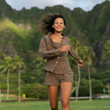 Woman wearing loose button up, smocked tube top and short in medium brown linen.