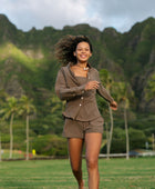 Woman wearing loose button up, smocked tube top and short in medium brown linen.