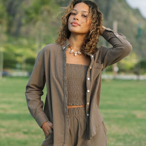 Woman wearing loose button up, smocked tube top and short in medium brown linen.