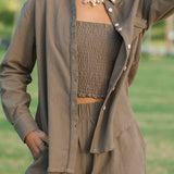 Woman wearing loose button up, smocked tube top and short in medium brown linen.
