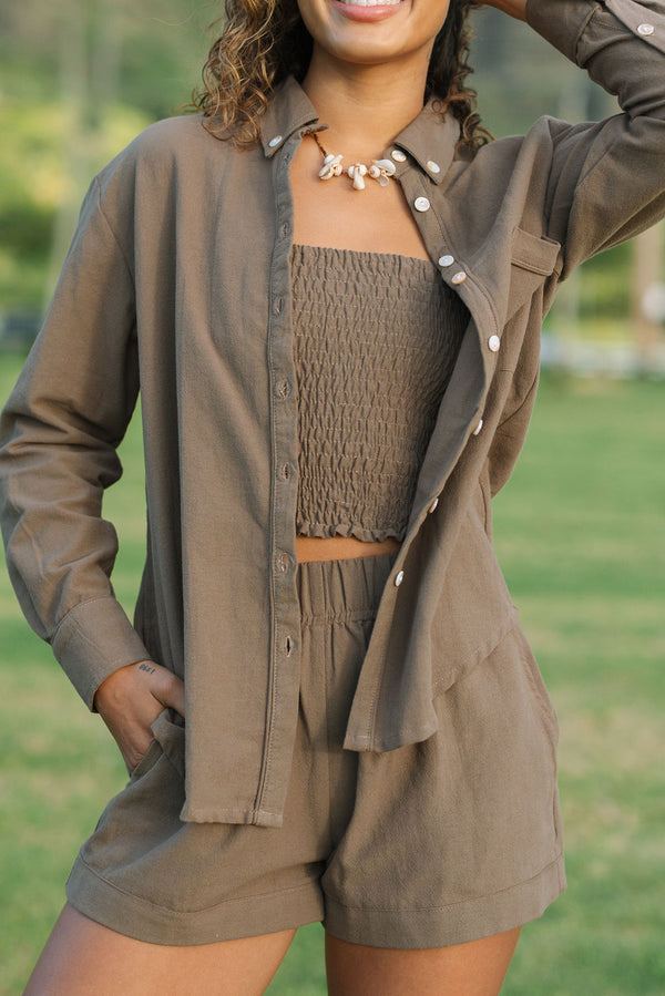 Woman wearing loose button up, smocked tube top and short in medium brown linen.