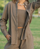 Woman wearing loose button up with smocked tube top and short in medium brown linen.