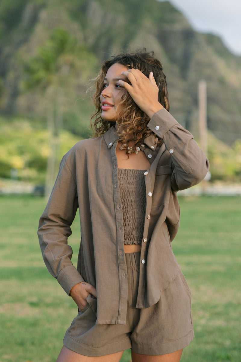 Woman wearing loose button up, smocked tube top and short in medium brown linen.