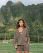 Woman wearing loose button up, smocked tube top and short in medium brown linen.