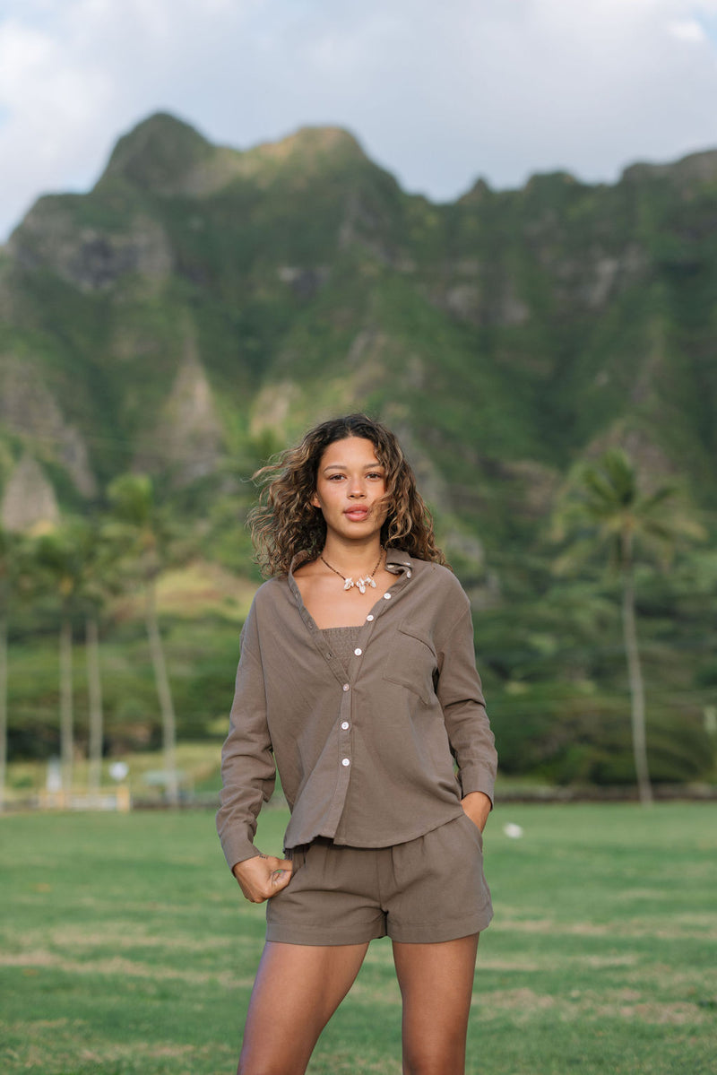 Woman wearing loose button up, smocked tube top and short in medium brown linen.