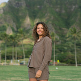 Woman wearing loose button up, smocked tube top and short in medium brown linen.