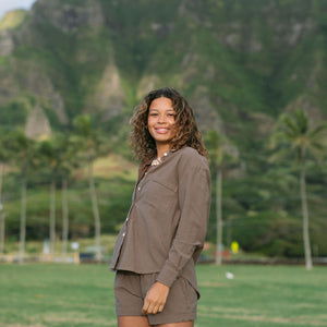 Woman wearing loose button up, smocked tube top and short in medium brown linen.