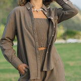 Woman wearing loose button up, smocked tube top and short in medium brown linen.