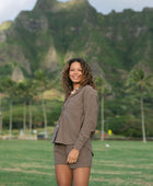 Woman wearing loose button up, smocked tube top and short in medium brown linen.