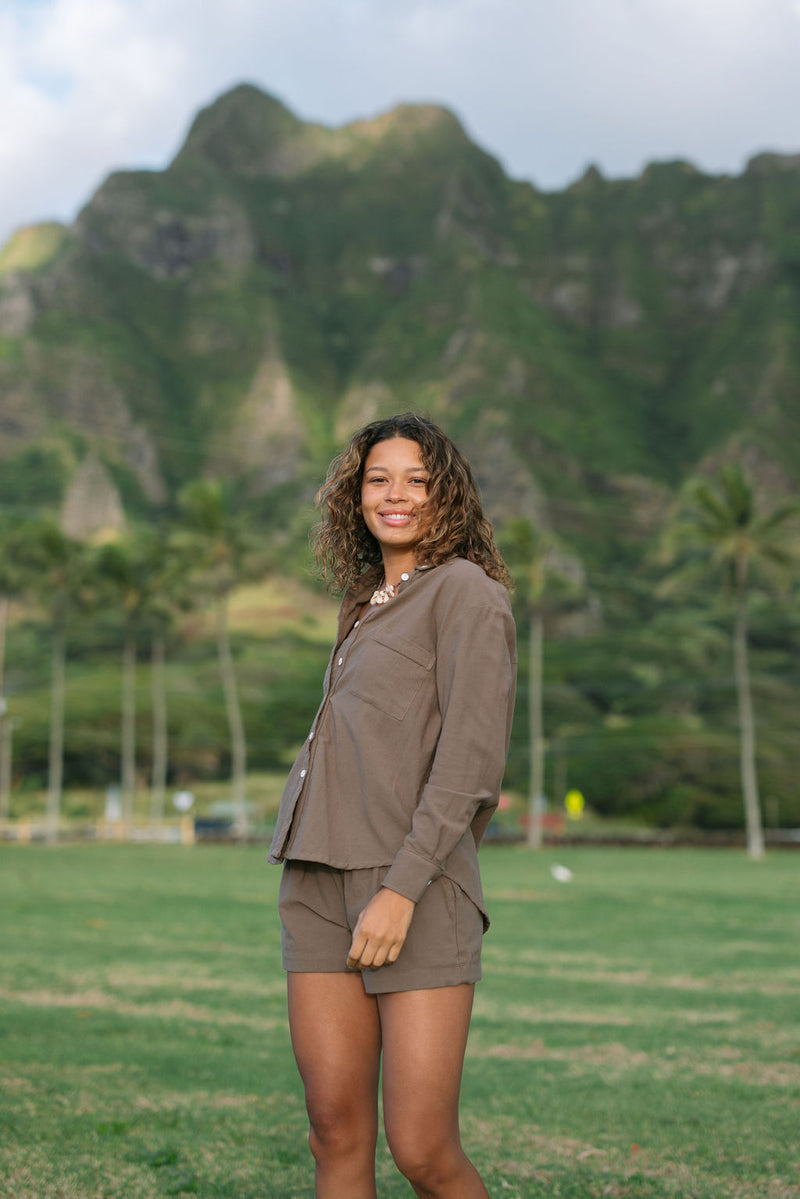 Woman wearing loose button up, smocked tube top and short in medium brown linen.