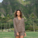 Woman wearing loose button up, smocked tube top and short in medium brown linen.