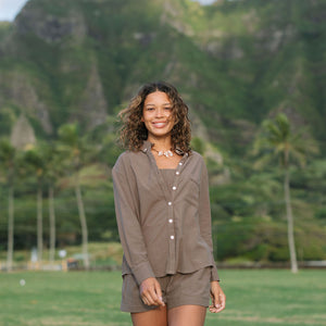 Woman wearing loose button up, smocked tube top and short in medium brown linen.