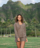 Woman wearing loose button up, smocked tube top and short in medium brown linen.